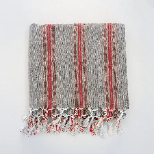 Turkish towel that has a flat weave and has brown, rusty red, and very thin turquoise stripes.