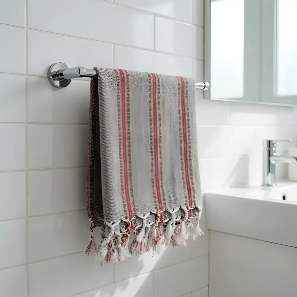 Gray turkish hand towel with red stripes and fringed edges hangs on chrome rack made of premium cotton hand towels