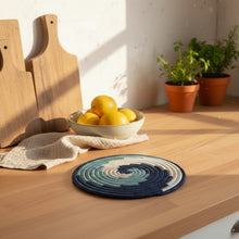 Handmade eco-friendly rususa trivet circular placemat with navy blue teal and cream spirals handcrafted design