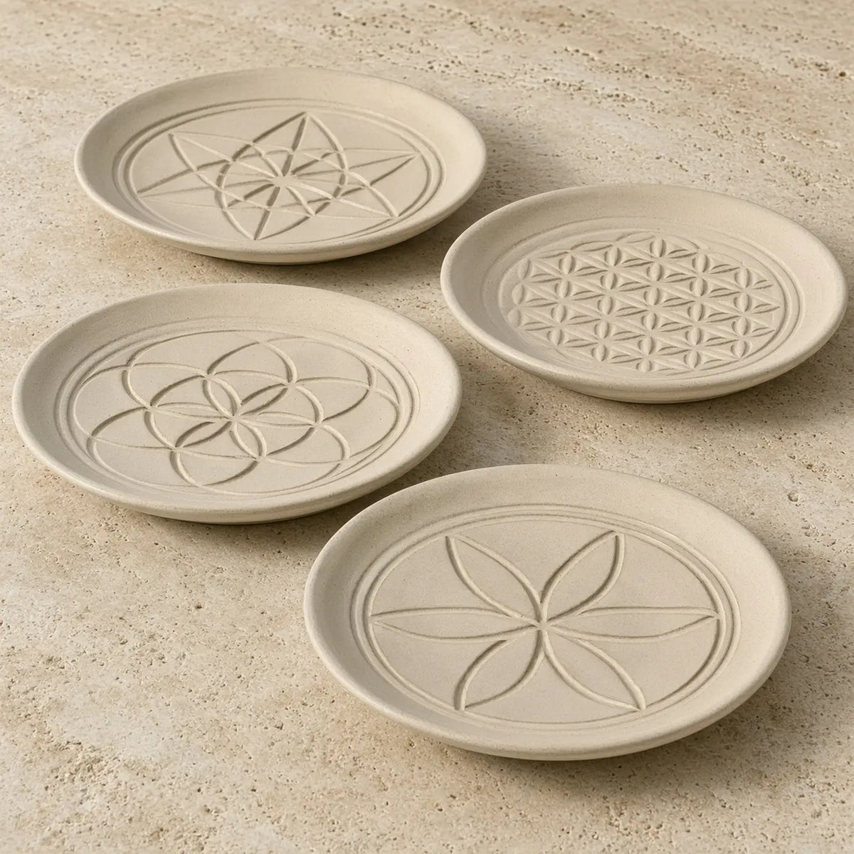 Set of four beige ceramic sacred designs appetizer coasters with unique embossed patterns and geometric designs
