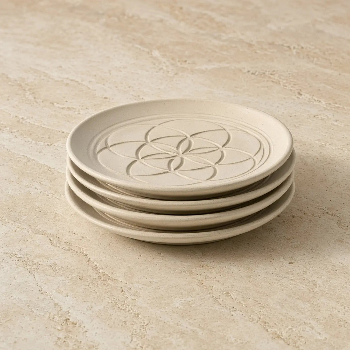 Stack of cream-colored ceramic sacred designs appetizer plates with unique embossed patterns flower-of-life design