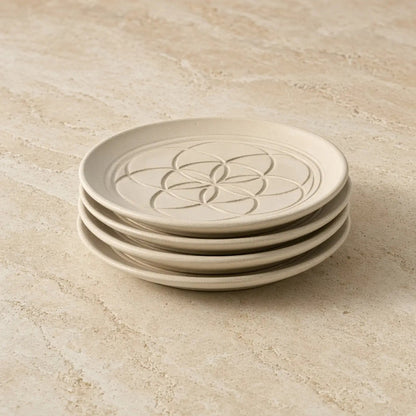 Stack of cream-colored ceramic sacred designs appetizer plates with unique embossed patterns flower-of-life design