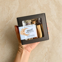 Black rectangular sacred space ritual kit with clear window holding dried herbs and palo santo stick for creating intentional space