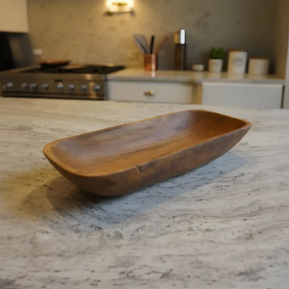 A rustic hand-carved salvaged teak root teak oval bowl with warm brown finish perfect for bread bowls