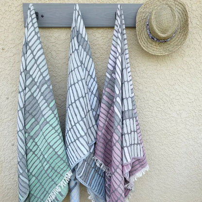Cotton towel with gauze texture with a geometric woven design and eyelash fringe.