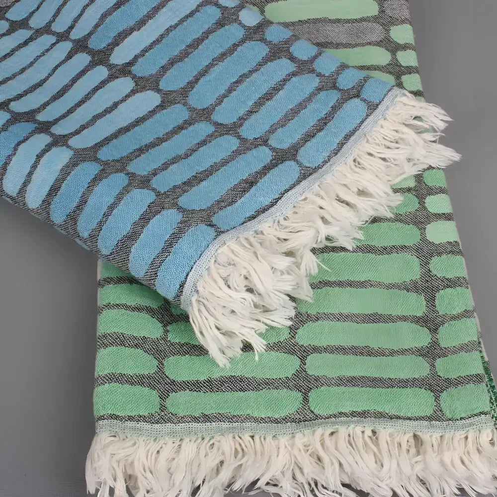 Cotton towel with gauze texture with a geometric woven design and eyelash fringe.