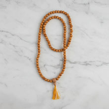 A sandalwood mala with 8 mm natural-toned wooden beads and a small cotton tassel made from sustainably sourced wood