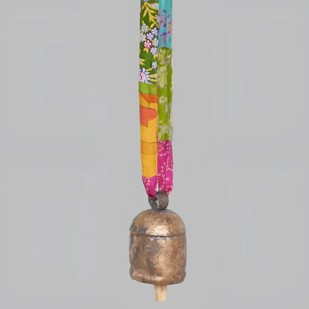copper bell hanging on a colorful fabric ribbon