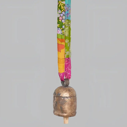 copper bell hanging on a colorful fabric ribbon