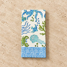 A rectangular white cotton napkin set featuring vibrant blue and green sea life napkins with fish octopus crabs and coral block print