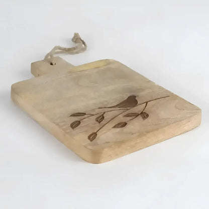 wooden serving board with etched bird on branch on a light background