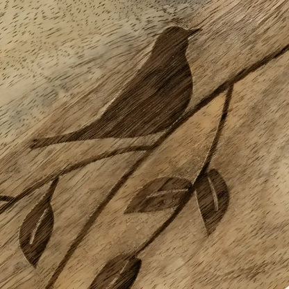wooden serving board with etched bird on branch.