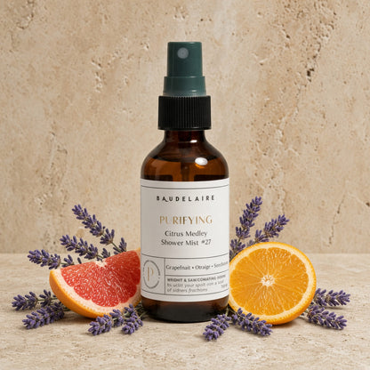 Brown glass shower spray mist with dark green nozzle labeled baudelaire purifying vibrant citrus medley 2oz surrounded by citrus slices and lavender