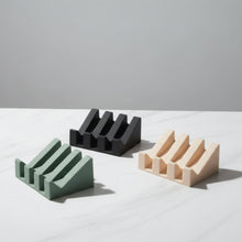 Three minimalist silicone soap dish stands in matte black, olive green, beige