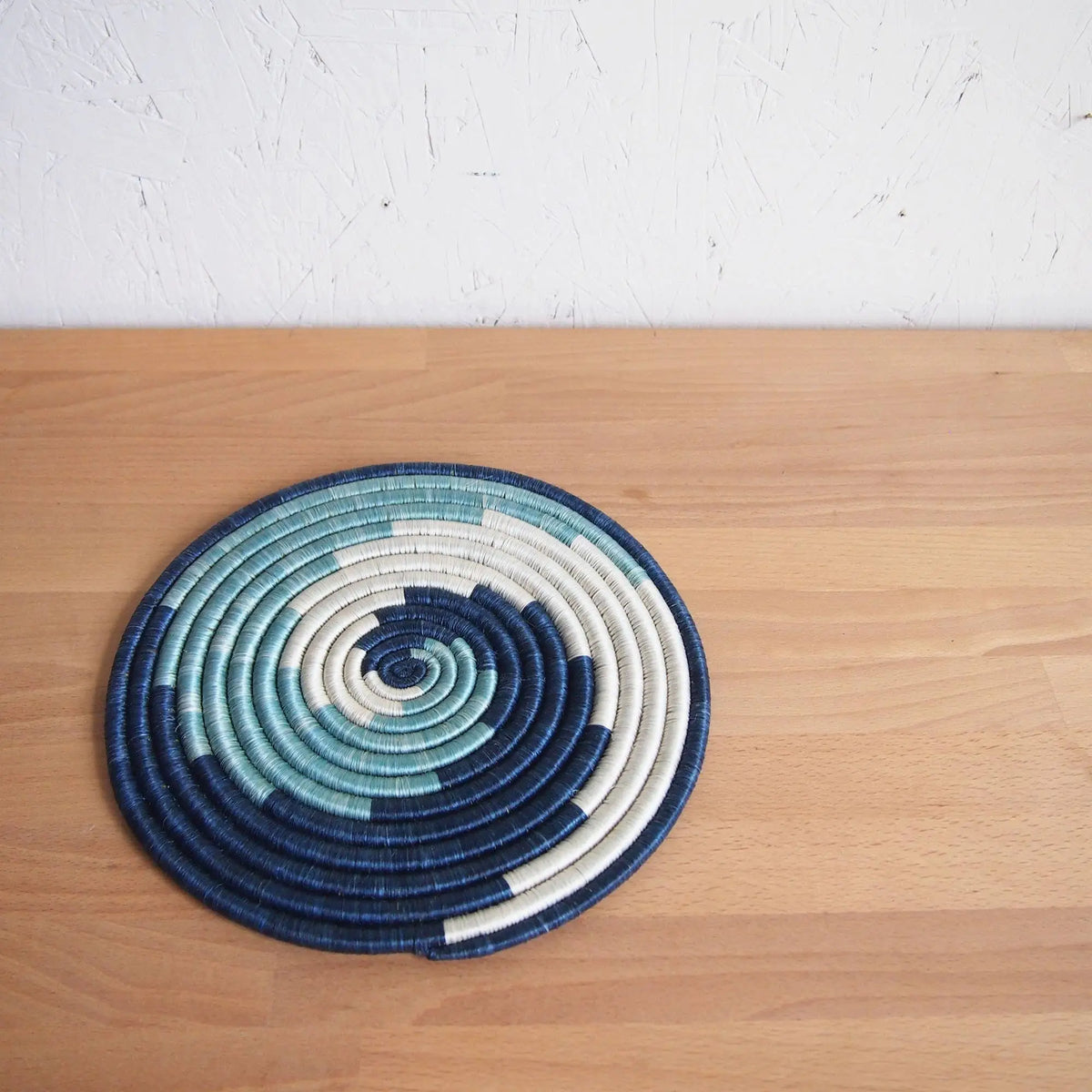 Handmade eco-friendly rususa trivet circular placemat with navy blue teal and cream spirals handcrafted design