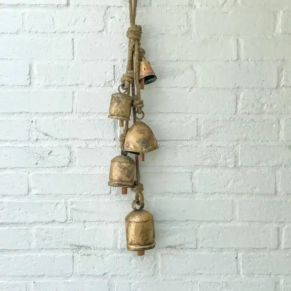Bronze bella yied to a rope hanging on a wall.
