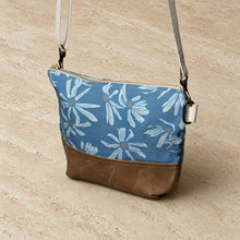 Small crossbody bag in blue and tan with artisan-designed white daisy pattern made from waxed canvas for durability