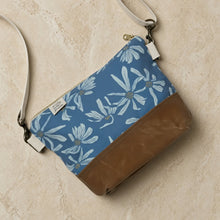Small crossbody bag with blue daisy design featuring waxed canvas durability brown leather bottom and white strap