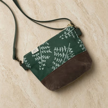 Small crossbody bag with artisan-designed fern pattern in dark green waxed canvas and brown leather bottom