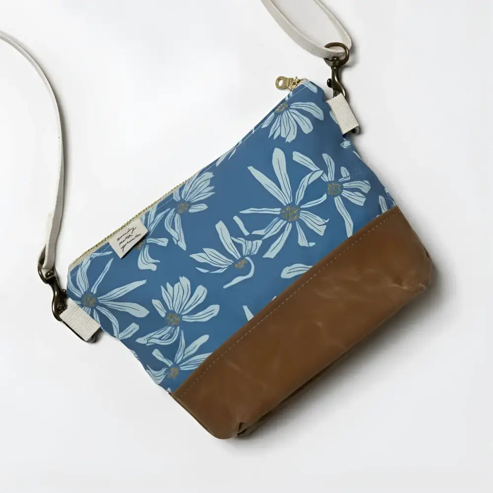 Small crossbody bag in blue canvas with white daisy pattern and brown leather bottom perfect for casual use