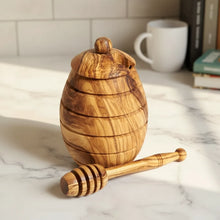 Small handmade olive wood honey jar with dipper featuring natural grain and warm golden brown tones