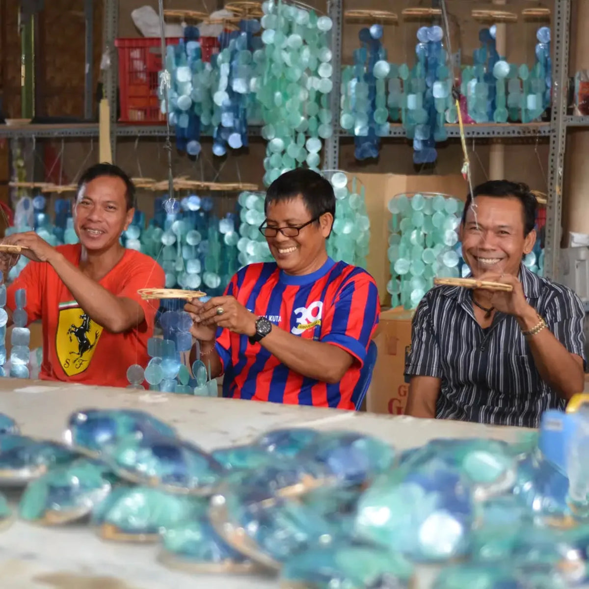 Small round handmade eco-friendly capiz chimes in blue, green, and purple hanging in translucent clusters