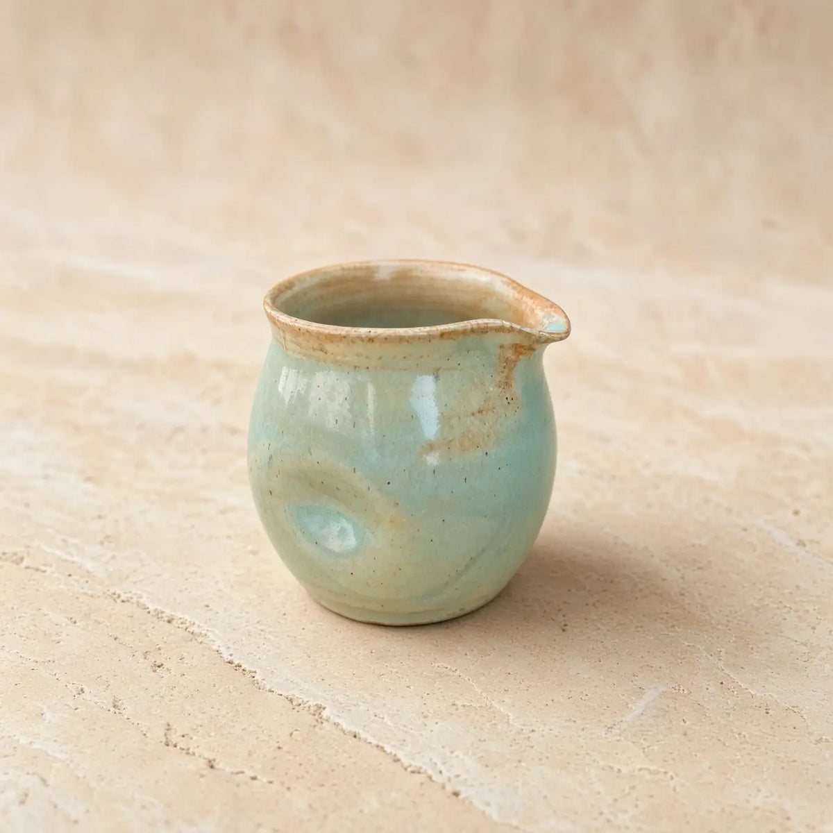 Small thumb divot handmade pitcher 8 oz with celadon glaze and earthy speckles perfect for pouring cream without awkward grip
