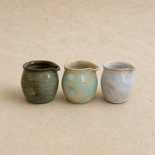 Three small thumb divot handmade pitchers in muted green blue-green and pale gray perfect for pouring cream with awkward grip