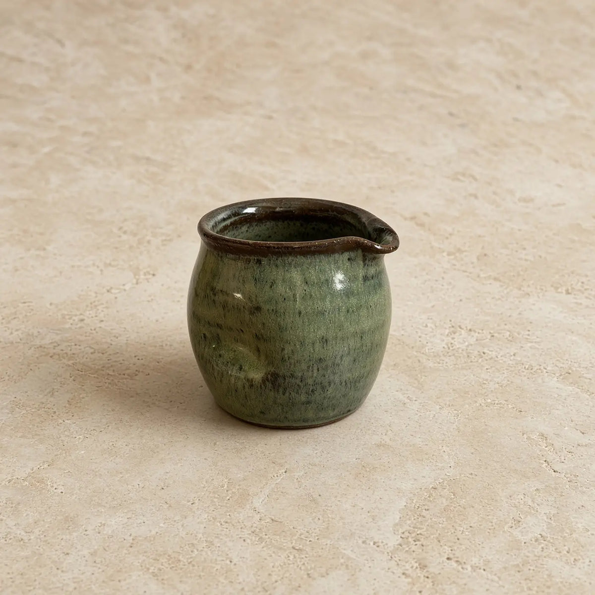 Small thumb divot handmade pitcher 8 oz ceramic with mottled green glaze and dark brown rim for pouring cream