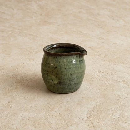 Small thumb divot handmade pitcher 8 oz ceramic with mottled green glaze and dark brown rim for pouring cream