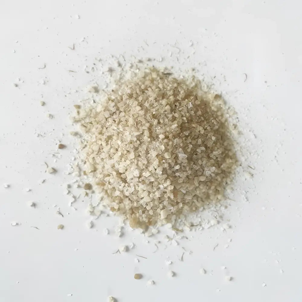 A mound of pale beige soaking salts with coarse translucent crystals featuring mustard seed for cold muscle relief