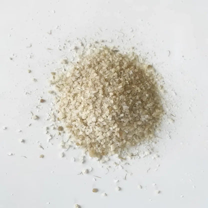 A mound of pale beige soaking salts with coarse translucent crystals featuring mustard seed for cold muscle relief