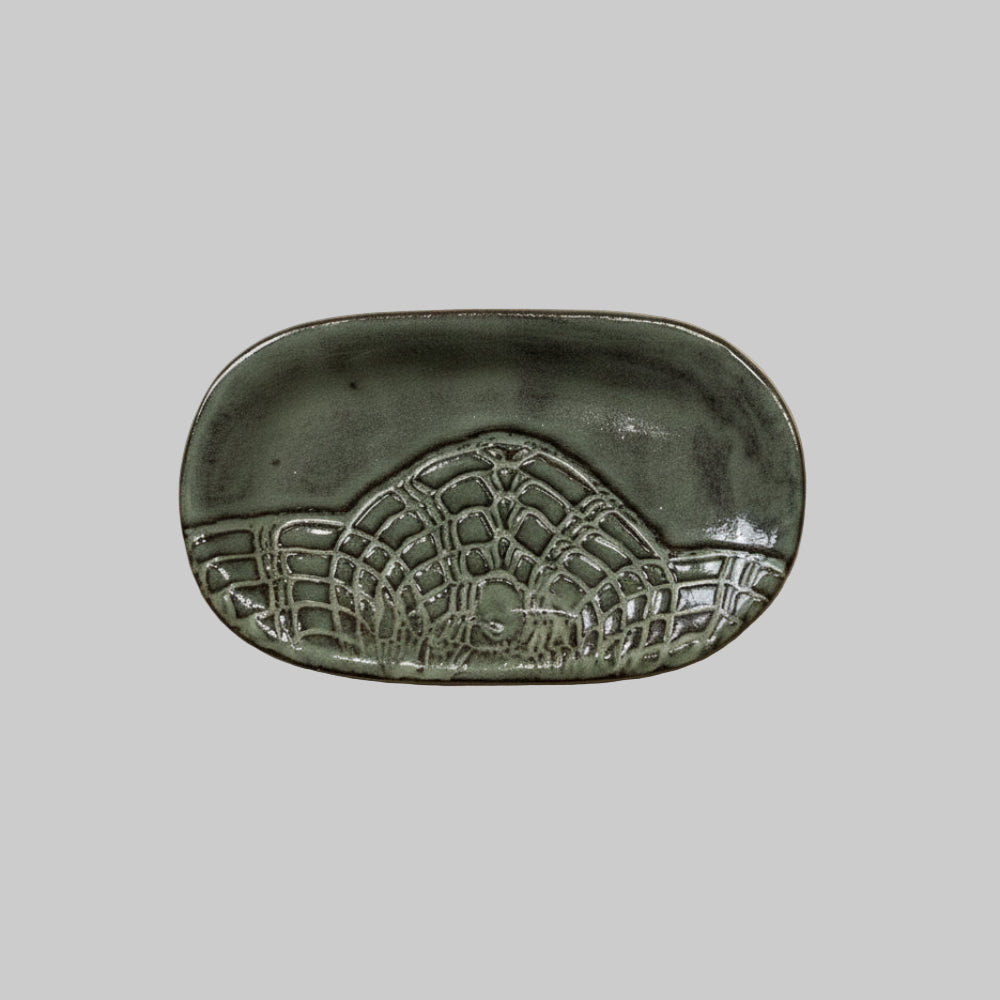 Decorative ceramic dish with embossed design on a neutral background