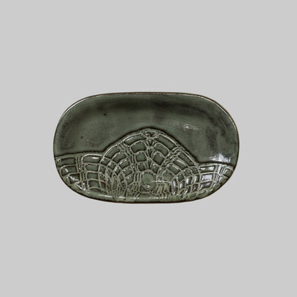 Decorative ceramic dish with embossed design on a neutral background