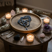 A coiled blue sodalite mala with 6 mm beads and beaded tassel resting on a wooden tray for mantra chanting and meditation companion