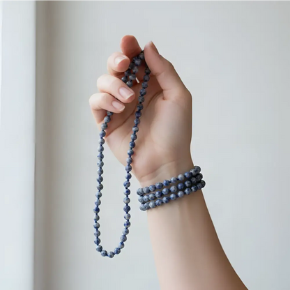 A hand holds a sodalite mala meditation companion with dark blue beads and beaded tassel for mantra chanting