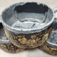 Handmade pottery bowl with gray glaze on the top and inside and black and brown floral design on the outside.