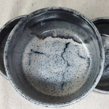 Handmade pottery bowl with gray glaze on the top and inside and black and brown floral design on the outside.