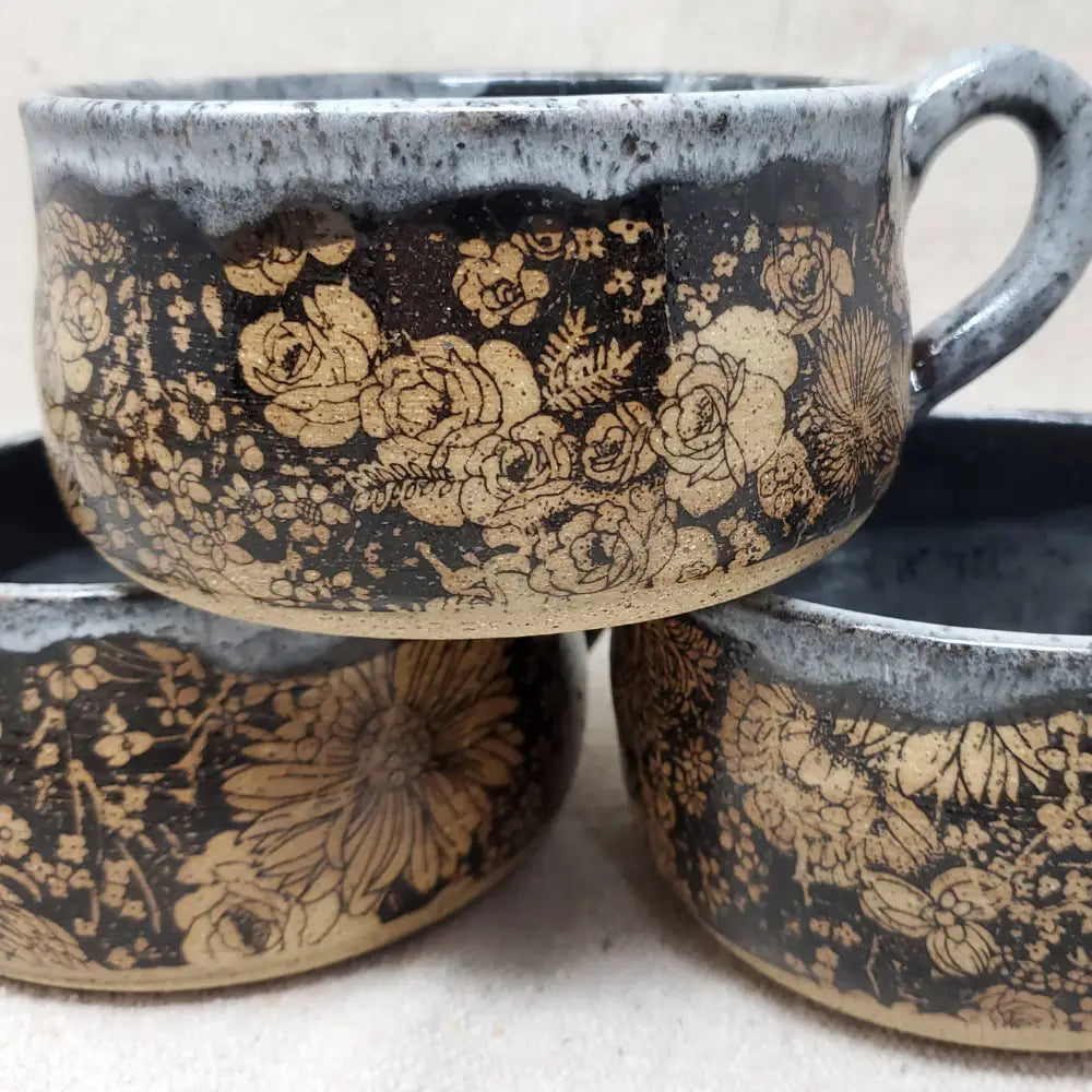 Handmade pottery bowl with gray glaze on the top and inside and black and brown floral design on the outside.