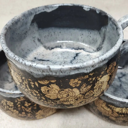 Handmade pottery bowl with floral design and speckled blue and white interior glaze