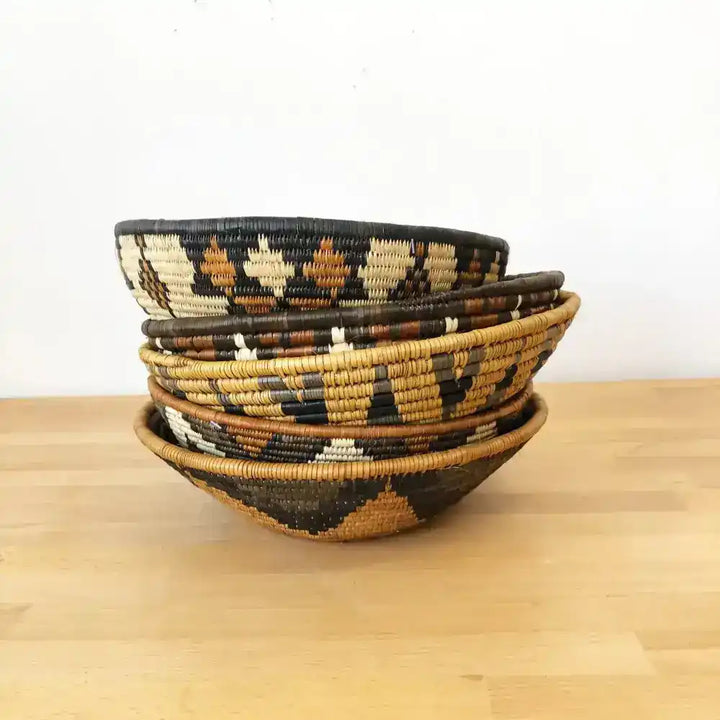 Assorted handmade African baskets in various natural colors with striking geometric designs.