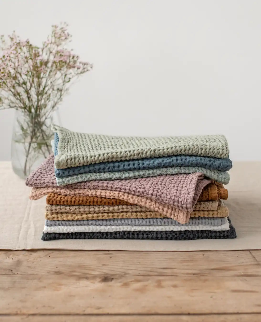 A stack of waffle-weave dishcloths in various muted colors.