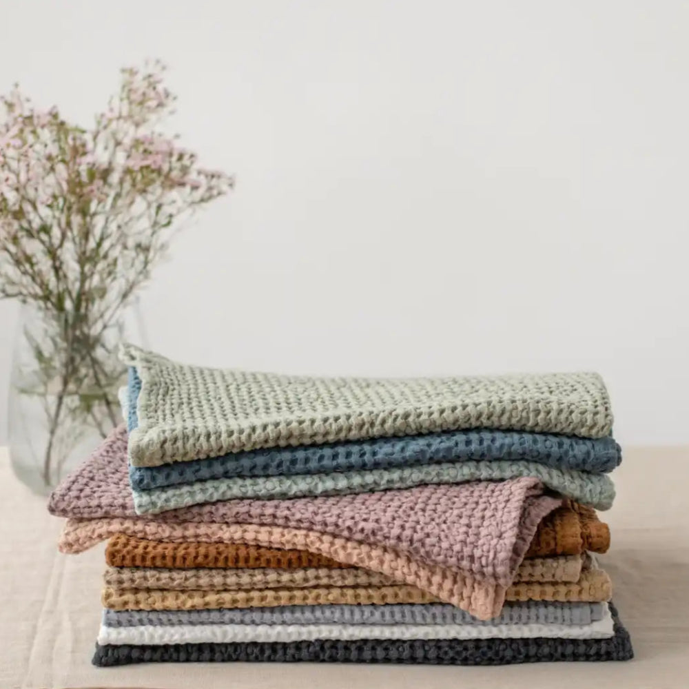 A stack of waffle-weave dishcloths in various muted colors.