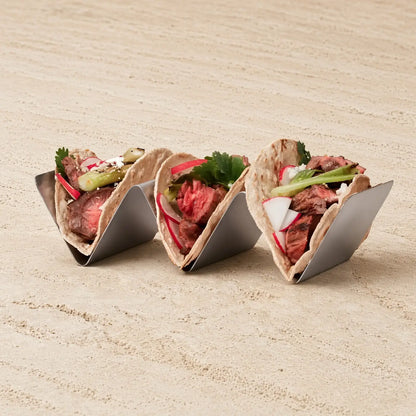 Three stainless steel upright taco racks holding grilled meat and fresh veggie filled tortillas for easy serving