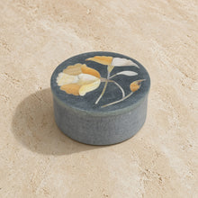A round dark gray palewa stone bloom box with delicate yellow and white floral inlay by tara projects trinket box