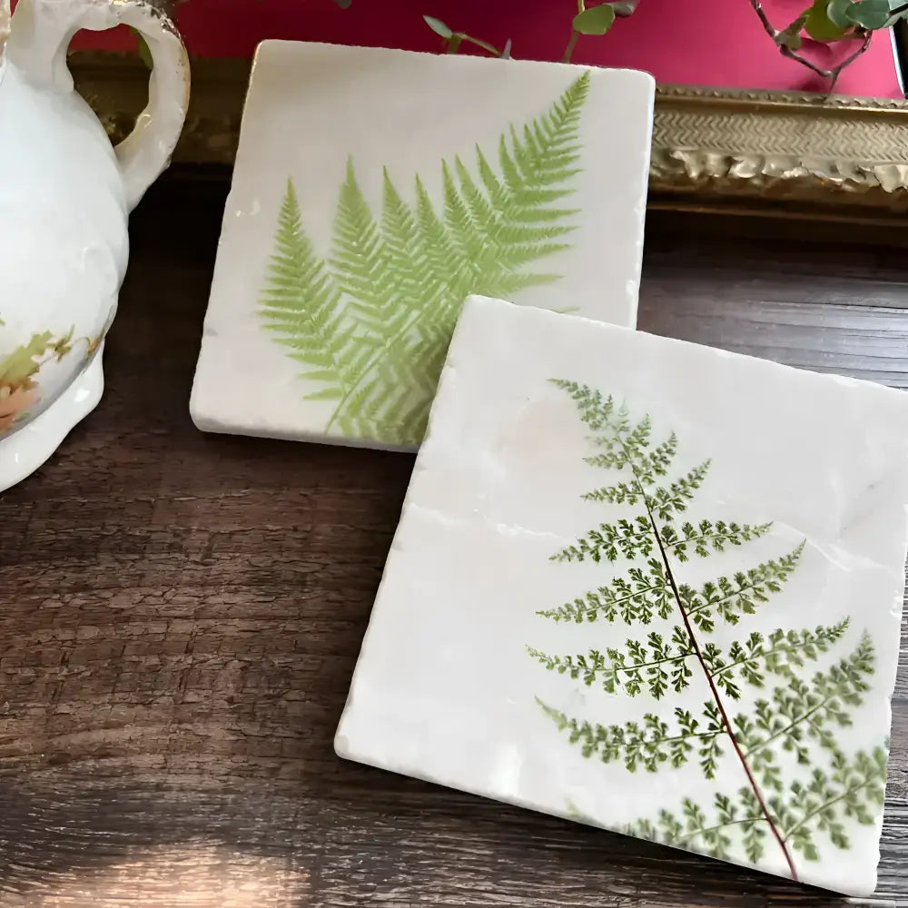 two stone tiles with fern design on a wooden table