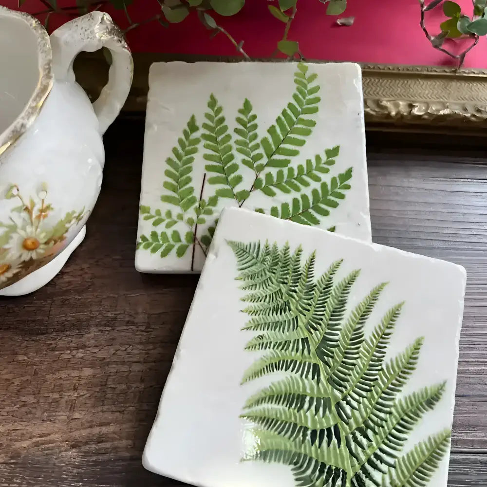 two stone tiles with fern design on a wooden table