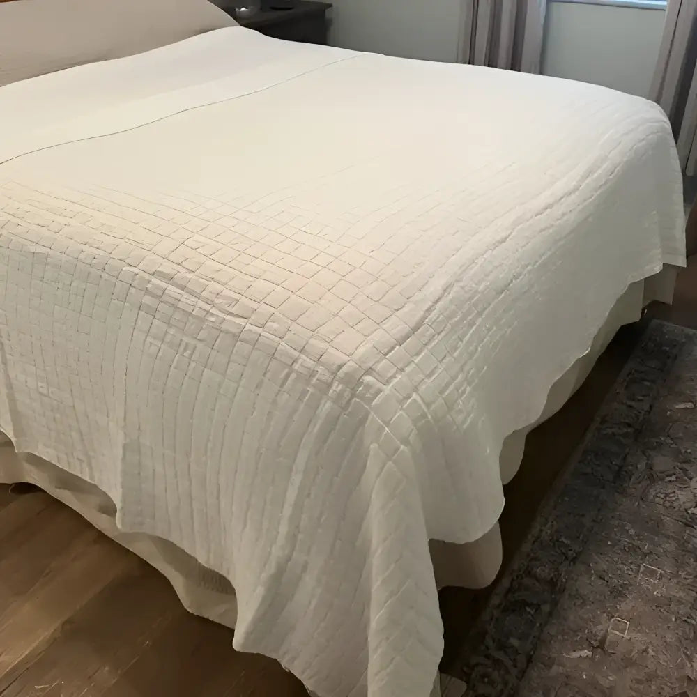White quilted blanket on a bed in a bedroom setting