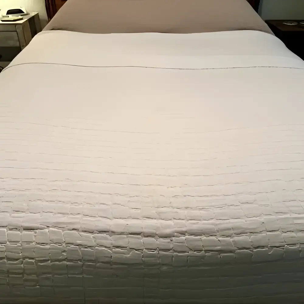 Textured white bedspread on a bed with a neutral background