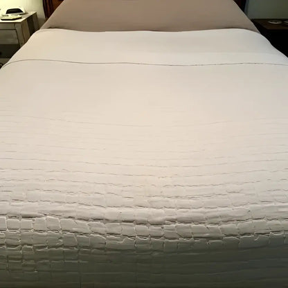 Textured white bedspread on a bed with a neutral background